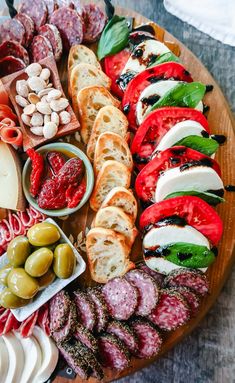 an assortment of meats and cheeses on a wooden platter with olives