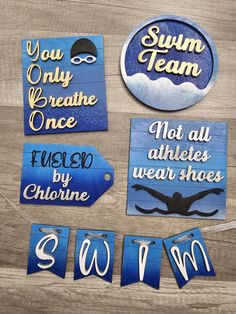 some blue and white signs on a wooden table next to each other with the words swim, you only breathe once not all athletes wear shoes