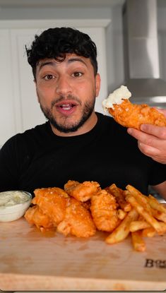 a man is holding up some food to his face as he looks at the camera