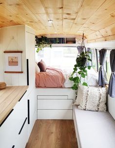 the interior of a small camper with a bed, window and plants in it