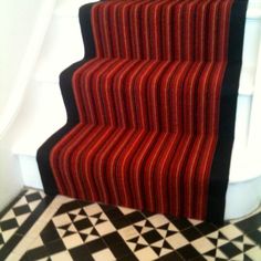 a stair case with red and black stripes on the bottom, next to a checkered floor