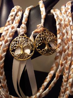 a pair of tree of life bracelets with white and gold braiding on display