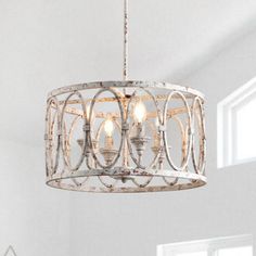 a white chandelier hanging from the ceiling in a room with windows and furniture