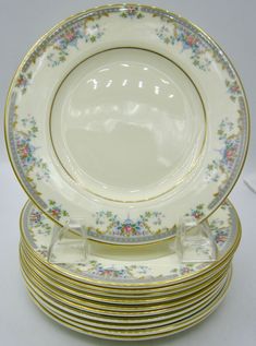 a stack of white and gold plates stacked on top of each other with floral designs