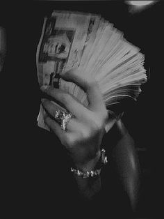 black and white photograph of a woman covering her face with money