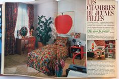 an article in the magazine shows a bedroom with colorful furniture and decor, including a bed