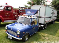 an old truck with a camper on the back parked next to a red and white truck