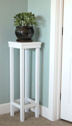 a small white table with a potted plant on top