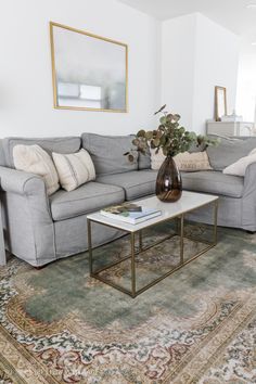 a living room with a couch, coffee table and rugs on the floor in front of it