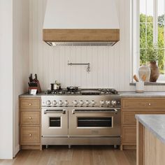 a stove top oven sitting inside of a kitchen next to wooden cabinets and counter tops