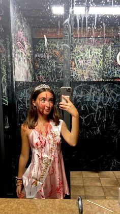 a woman with makeup on taking a selfie in front of a mirror covered in graffiti