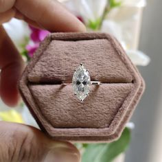 a person holding up a ring with a diamond in it's center and on its finger