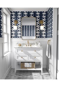 a bathroom with blue and white wallpaper, two sinks and a gold framed mirror