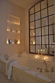 a bathtub with candles on the wall next to it and a window in the background