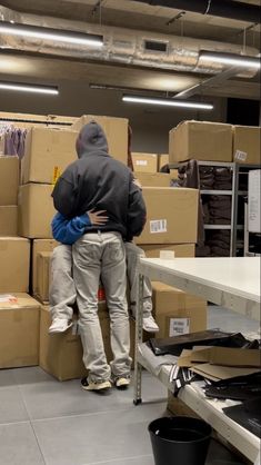 two people hugging each other in front of boxes