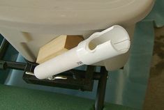 a white toilet sitting on top of a green floor next to a wooden block and plunger