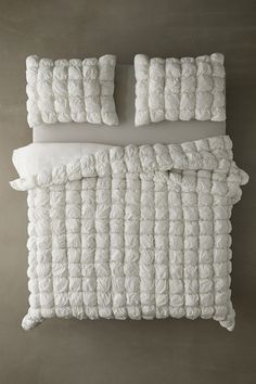 the bed is made up with white ruffled sheets and pillows on top of it