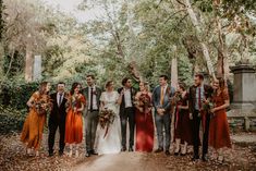 a group of people standing next to each other in front of some trees and bushes