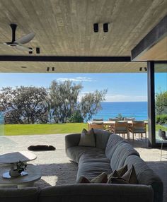 a living room with couches and tables overlooking the ocean from an open floor plan