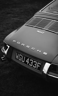 an old porsche parked on the grass in black and white with its license plate showing