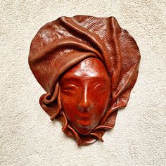 a wooden mask with a cloth draped over it's head on a white carpet