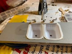 two white sinks sitting on top of a table next to some construction materials and tools