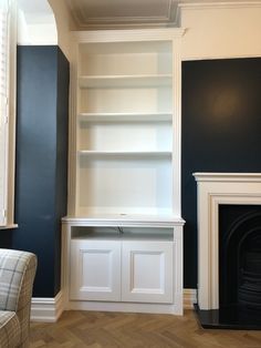 an empty living room with blue walls and white bookcases on the fireplace mantel