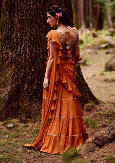 Editor's Note The Rust Orange 4- Layered Pre-draped Sari Comes With Dainty Gota Patti Borders Along With Naksha Embroidered Blouse Embellished With Dabka Work, Mirror, Moti, Cutdana And Zari Work Paired With Geometric Belt ; Works Well From Day Wear To Evening Look Color: Rust orange Fabric: Crepe Care: Dry Clean Only About the Designer Paulmi & Harsh is a luxury prêt label inspired by beautiful botanicals. Paulmi & Harsh design strong, feminine silhouettes with prints and delicate detailing, fu Festive Embroidered Draped Blouse Piece, Embroidered Draped Blouse Piece For Party, Bollywood Style Embellished Draped Blouse, Navratri Embellished Draped Blouse Piece, Bohemian Draped Sets For Festive Occasions, Festive Bohemian Draped Sets, Diwali Embellished Draped Blouse, Bohemian Georgette Blouse With Zari Work, Embellished Draped Blouse For Diwali