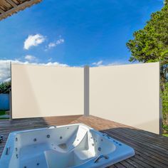 an outdoor jacuzzi tub sitting on top of a wooden deck next to a white privacy wall