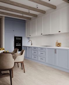 a large kitchen with blue cabinets and white counter tops, along with beige dining chairs