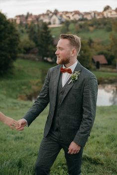 a man in a suit and bow tie holding hands