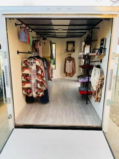 the inside of a small storage area with clothing on racks and clothes hanging from hooks