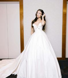 a woman in a white wedding dress posing for the camera with her hand on her hair