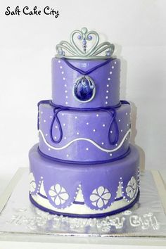 a three tiered cake with purple frosting and white designs on it's sides