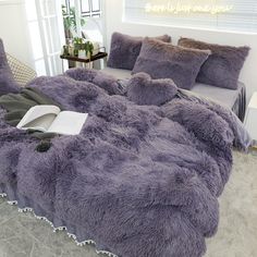 a bed covered in purple fluffy blankets and pillows