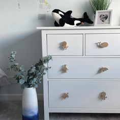 a white dresser with two drawers and a stuffed animal on top