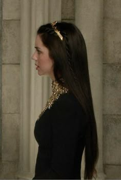 a woman with long brown hair wearing a black dress and gold jewelry on her neck