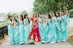 a group of women standing next to each other wearing blue and red outfits with flowers in their hair