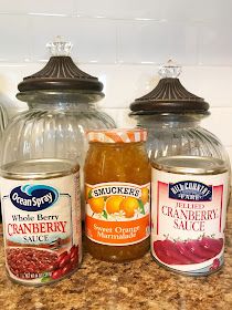 three jars of food sitting on top of a counter next to each other and one jar filled with cranberry sauce