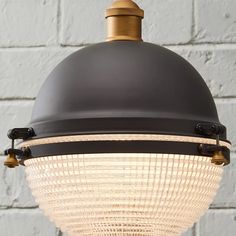 a light hanging from the ceiling in front of a white brick wall with black accents