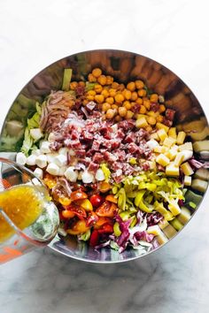 a large bowl filled with different types of vegetables and seasoning next to a glass of orange juice