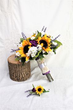 a bouquet of sunflowers and white carnations sits on a tree stump