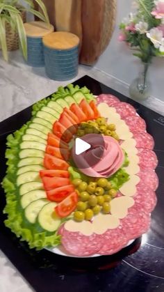 a platter filled with meat, vegetables and fruit on top of a black counter