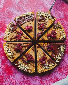 a cake with chocolate and nuts on it sitting on top of a pink table cloth