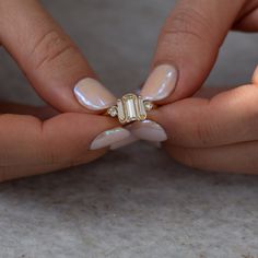 a woman's hands with white and gold manicures holding a diamond ring