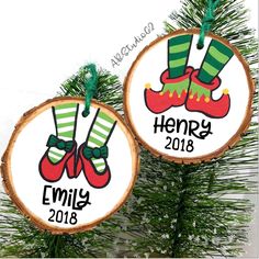 two personalized christmas ornaments hanging from a pine tree with green and red stockings on them