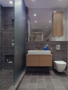 a bathroom with a toilet, sink and mirror in it's center wall area