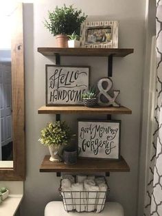 a bathroom with three shelves above the toilet and two plants on top of it, in front of a mirror