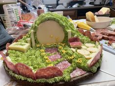 a cake made to look like a house with green grass and fruit around it on a table