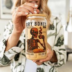 a woman holding up a jar with a skeleton on it's lid and the label for dry bones